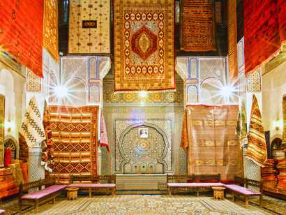 Vivid Moroccan rugs set against historic Fez walls, representing the richness of its living traditions
