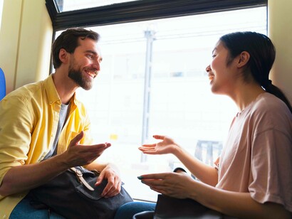 Due giovani passeggeri chiacchierano e ridono seduti su un treno, godendosi il viaggio e la compagnia reciproca