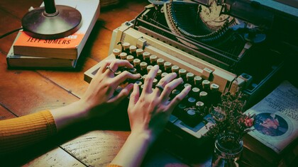 A lady busy writing on her typewriter