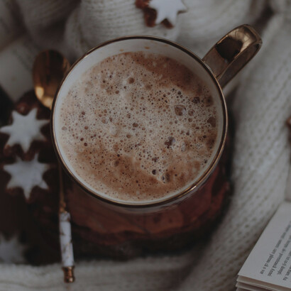 A steaming cup of hot chocolate placed on a soft white wool sweater, capturing a cozy winter mood and the comforting link between chocolate, serotonin, and happiness