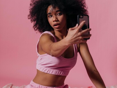 Mulher se fotografa com seu celular. Outro exemplo foi um usuário que dizia não achar outros perfis bonitos no app e que o meu perfil falso era a única bonita ali, quando mostrei vários outros perfis com diversas meninas normais e bonitas (e até coloquei o meu no meio) o usuário respondeu que “elas não eram bonitas suficientes” e que “só o meu perfil (falso) que fazia o tipo dele”. Esse exemplo só mostra o quão irreal é a visão da maioria dos usuários (principalmente masculinos) nos apps de relacionamento, pois o próprio usuário com quem conversei nesse exemplo tinha uma beleza comum, podendo ser até considerado feio por outras pessoas



