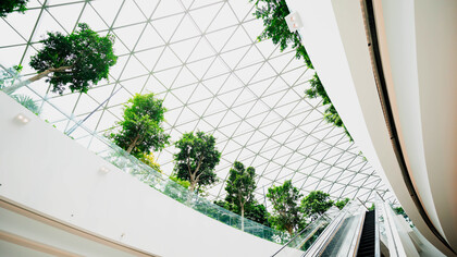 The lush greenery within the glass dome of the building illustrates the concept of regenerative design, where buildings create and renew their own resources