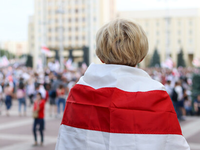 Niño se arropa con la bandera en una plaza pública en Minsk, Bielorrusia