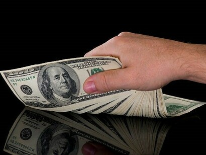 A person clutching a stack of cash in their hand