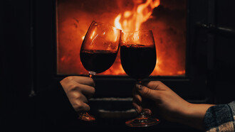 Un brindis con vino tinto en mitad de la noche frente a una chimenea