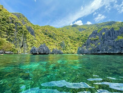 The crystal waters of El Nido, Palawan beneath a bright sky, reflecting the fragile paradise threatened by environmental decline