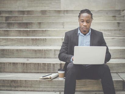 A man on the steps of a building trying to use the internet effectively in Africa