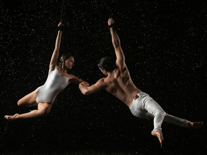 Hombre y mujer practicando acrobacia bajo la lluvia
