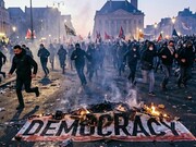 A banner of democracy burning in midst a protest, symbolising a crisis of confidence in elected leadership