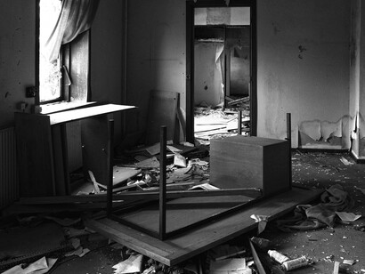 Escena de desorden y abandono. Una habitación deteriorada con una mesa volcada y escombros en el suelo