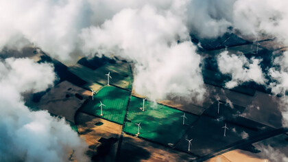 Aerial view of wind turbines standing tall near a vast field, symbolizing the synergy between renewable energy and agriculture
