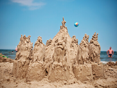 A sand castle made on the beach is beginning to break