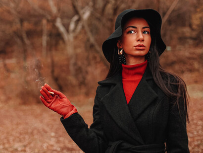 Mujer sostiene un cigarrillo en un ambiente otoñal