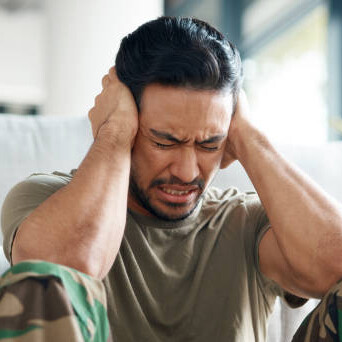 A soldier sitting on a sofa in uniform, showing signs of trauma and depression — a reflection of stress, anxiety, and PTSD in military life