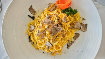 Un piatto di lusso: spaghetti arricchiti con abbondanti scaglie di pregiato tartufo nero, per un'esperienza gastronomica unica e sofisticata