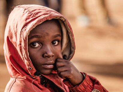 With a piercing gaze that reflects his reality, this young boy invites us to confront the stark truth of poverty and the urgent need for systemic change