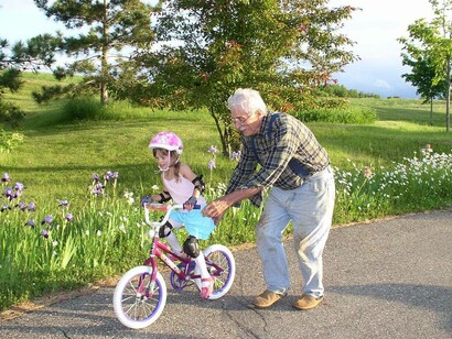 Nonno che aiuta la nipotina ad andare in bicicletta