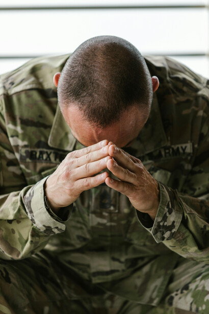 Un miembro del ejército toma su cabeza en señal de decaimiento, padece las consecuencias de enfrentarse en un conflicto bélico