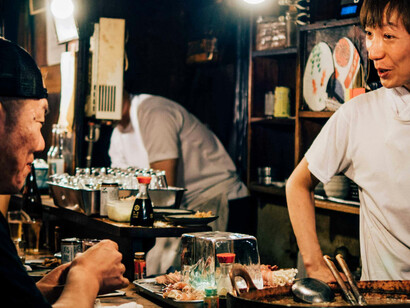 L'échange discret et respectueux entre le chef et le client reflète l'esprit de partage et de culture japonaise, où chaque plat devient un acte culturel unique