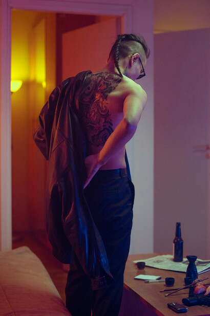 A Japanese man displaying a full-back tattoo outside a traditional house