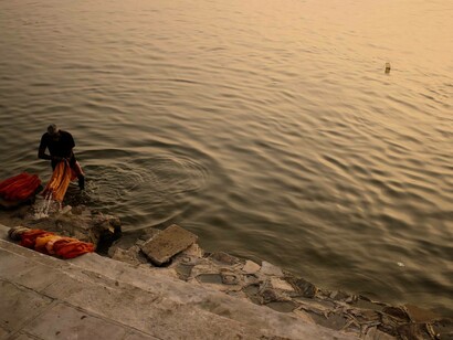 Uomo lava dei vestiti nel fiume Gange, India