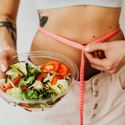 A health-conscious woman savors a colorful vegetable salad, embracing balanced nutrition and mindful calorie tracking