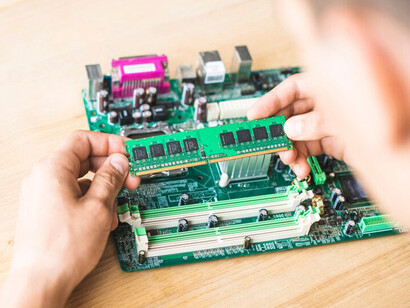 An IT technician working on hardware repairs, focusing on neuromorphic chips, at a wooden table
