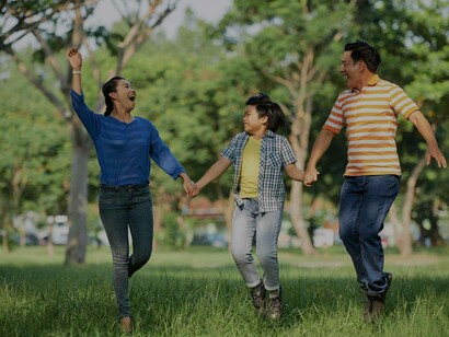 Parents walking and skipping with their child in the park on a sunny day expressing joy and the splendid benefit of being parents