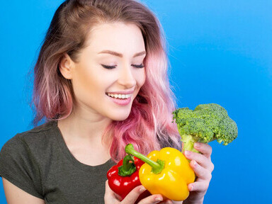 A healthy woman examining fresh broccoli, red and yellow peppers—key ingredients of the Mediterranean diet—supporting the gut-brain axis and promoting a healthy gut flora in nutritional psychiatry