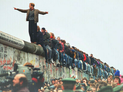 Persone sedute in cima al muro di Berlino il giorno della caduta, il 9 novembre 1989, Berlino, Germania