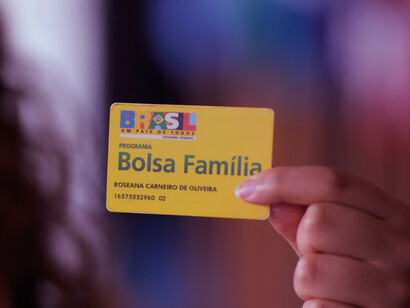 Holding her Bolsa Família card with joy, this young woman embodies the success of a program that continues to lift millions out of poverty and foster economic growth in Brazil