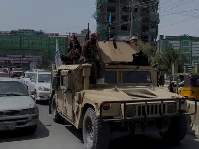 Taliban fighters ride in a captured Humvee after the Fall of Kabul in August 2021