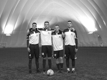 Group of young football players standing on a green training pitch at a modern football academy facility