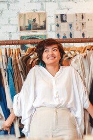 Moça alegre em loja de roupas secondhand