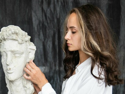 Mulher toca em escultura.  Novos estilos de vida em prol de respeito, orientação, apreciação e paixão pela transmissão cultural. Porque hoje, mais importante do que ver, é mostrar que se esteve lá. Sob o peso da vaidade, e da eterna infantilidade