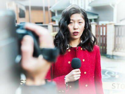 Presentadora de noticias reportando desde la escena de un crimen con su camarógrafo filmando