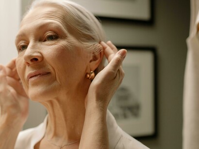 An older woman getting ready in the bathroom, reflecting aging with a sense of happiness