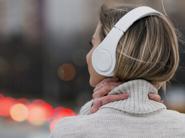 Woman on a rooftop, wearing headphones, captured from behind