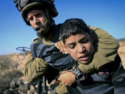 Un soldado israelí inmoviliza a un niño palestino