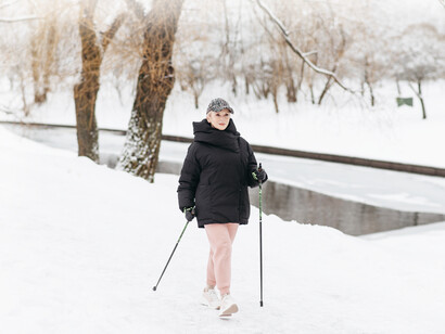 The older woman walking in the snow for exercise to keep fit as she gets older