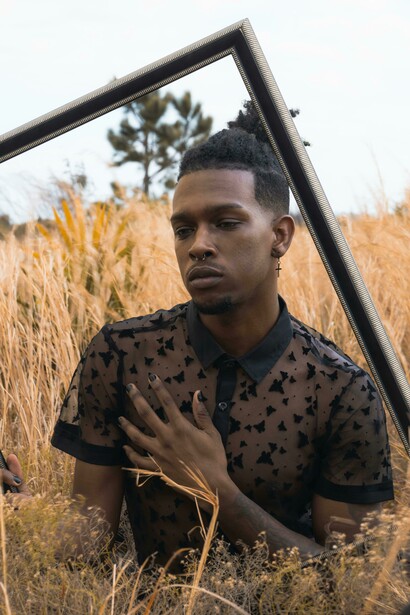 Self-expression online: a mirror selfie of an LGBTQ+ man in a black shirt embracing his identity