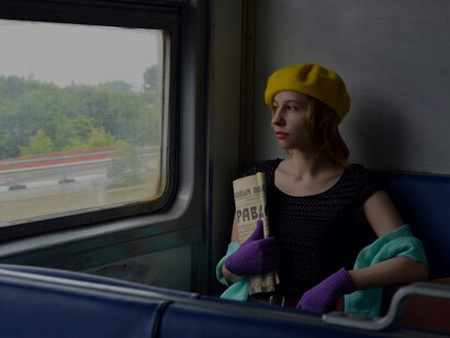 Witness the serene scene of a calm young woman engrossed in a Russian newspaper while awaiting her journey on a train in Russia, epitomizing the allure of exploration and discovery