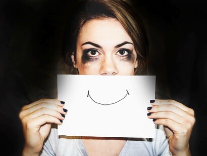 A young woman holding a smiley sign to let everyone know that she has beaten her anxiety