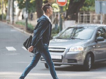 Young man taking an evening walk through the neighborhood, crossing the street