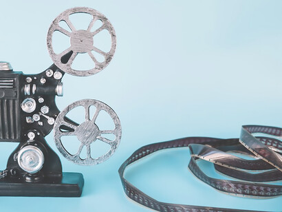 An overhead view presents film strips, a film reel, and various types of camcorders against a blue background, offering a comprehensive glimpse into the world of filmmaking and cinematography