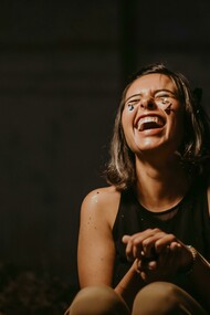 A photo of a woman laughing in a black top, capturing her funny and wonderfully weird energy