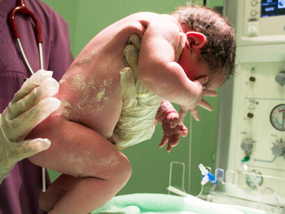 A nurse is gently holding a newborn baby in her arms