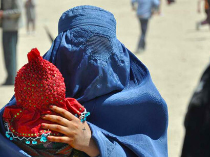An Afghan woman holding her baby while standing in line to receive supplies during a humanitarian mission in Kabul, Afghanistan