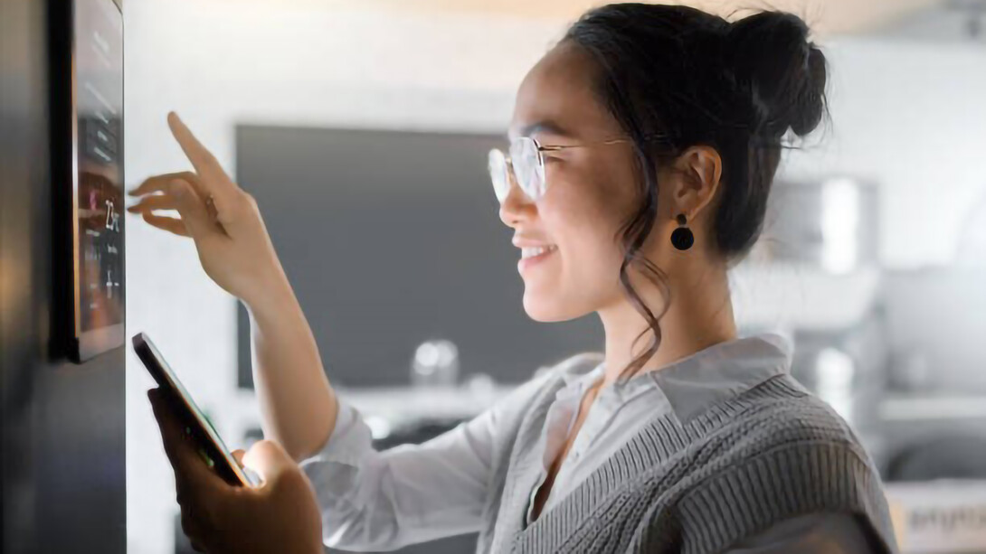 A smart home wall system, along with a smartphone, empowers a woman to monitor and control various aspects of house automation, including air conditioning and security networks