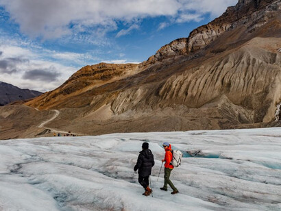 A group of people standing on a snow-covered slope, observing melting glaciers as a result of global warming